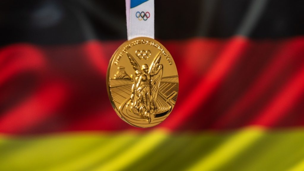 April 25, 2021 Tokyo, Japan. Gold medal of the XXXII Summer Olympic Games 2020 in Tokyo on the background of the flag of Germany.
