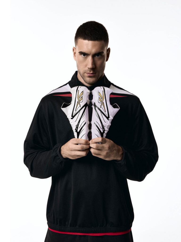 Dušan Vlahović holding a pair Reebok football boots. 