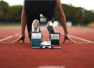Inside the Enhanced Games and its business model Track and Field Athlete being ready in the blocks alone with no competition, sprinter, empty lanes, lonely, training, practise, spikes