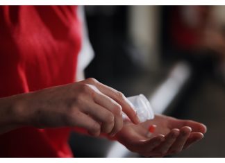 Do the Enhanced Games still work if the drugs don’t? Soccer player, hands and pills with vitamin supplement for sport, challenge or competition in locker room. Closeup, person or athlete with medication, antibiotic or prescription for game or match.