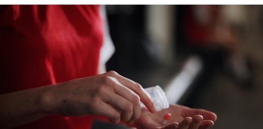 Soccer player, hands and pills with vitamin supplement for sport, challenge or competition in locker room. Closeup, person or athlete with medication, antibiotic or prescription for game or match.