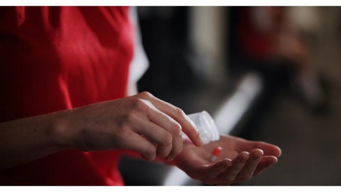 Drugs-in-sports-enhanced-games Soccer player, hands and pills with vitamin supplement for sport, challenge or competition in locker room. Closeup, person or athlete with medication, antibiotic or prescription for game or match.