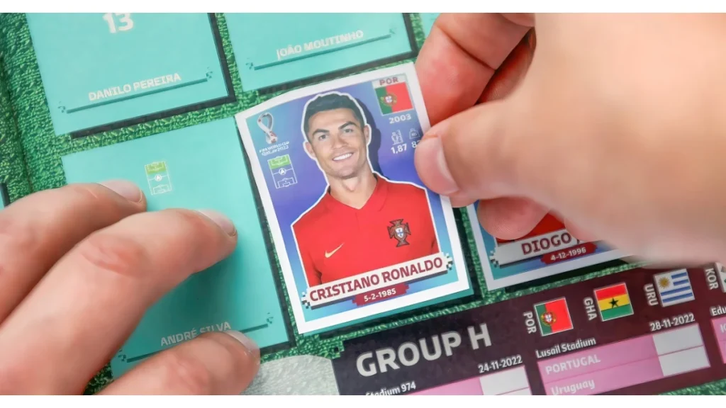 A football soccer ball fan adding a Panini sticker to a FIFA World Cup album.