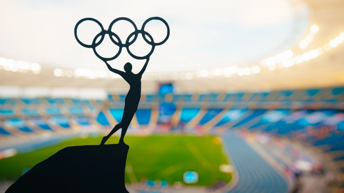 Statue of athletics Woman holding above head olympic circle. Modern Olympic Stadium in Background. Sport photo for Summer olympic Game in Paris 2024.