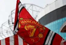 Disney+ finds backdoor into Manchester United’s fanbase Red Manchester United flag with club crest blows in the wind near Old Trafford stadium.