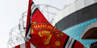 Disney+ finds backdoor into Manchester United’s fanbase Red Manchester United flag with club crest blows in the wind near Old Trafford stadium.
