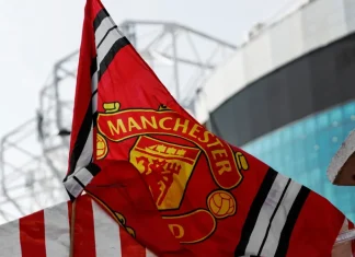 Disney+ finds backdoor into Manchester United’s fanbase Red Manchester United flag with club crest blows in the wind near Old Trafford stadium.