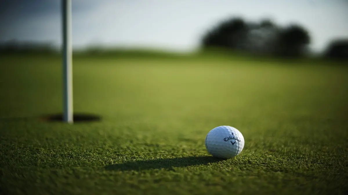 KANSAS CITY, UNITED STATES - Oct 11, 2021: A selective focus shot of a Callaway Golf ball near hole pin on a grass golf field.