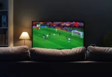 Is enforcement enough to stop £700m sports piracy losses? Football match on widescreen flat TV at home, sport and entertainment concept