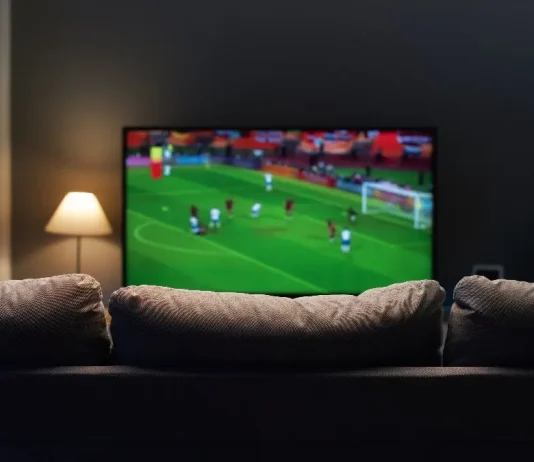 Is enforcement enough to stop £700m sports piracy losses? Football match on widescreen flat TV at home, sport and entertainment concept