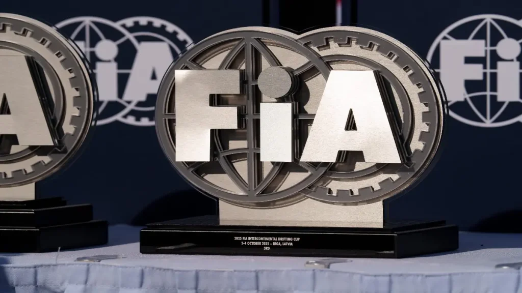Latvia, Riga 03-05.10.2025. FIA Drifting cup, two trophies sitting on top of a table covered with a white cloth In the background, there is a banner with the words FIA written on it.