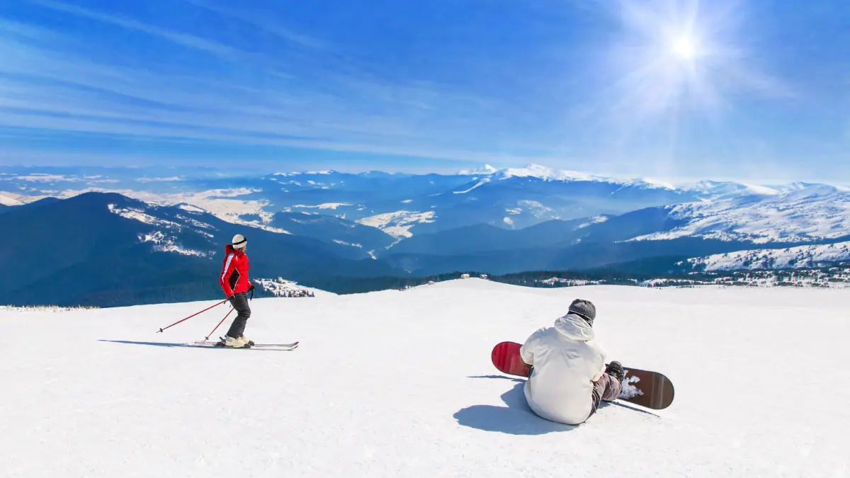 US Ski and snowboarder skiing and snowboarding downhill in high snowy mountains against sun sunshine, active winter sports holidays travel at ski health resort concept
